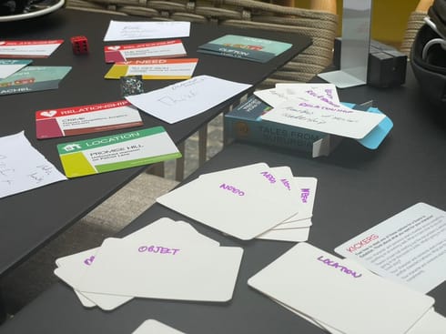 A table full of white cards with the words "object", "need", and "location" on, along with a few cards from the game Fiasco.